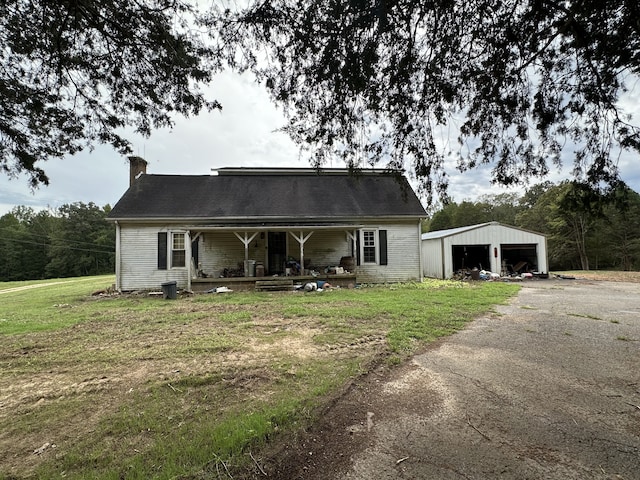 view of front of home featuring a porch, a front lawn, a garage, and an outdoor structure