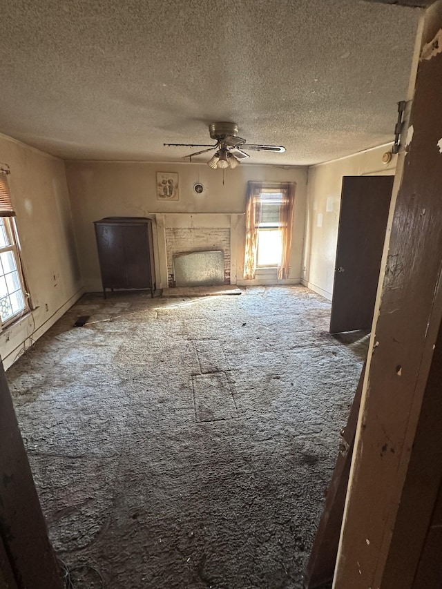 unfurnished living room with a textured ceiling, ceiling fan, and carpet