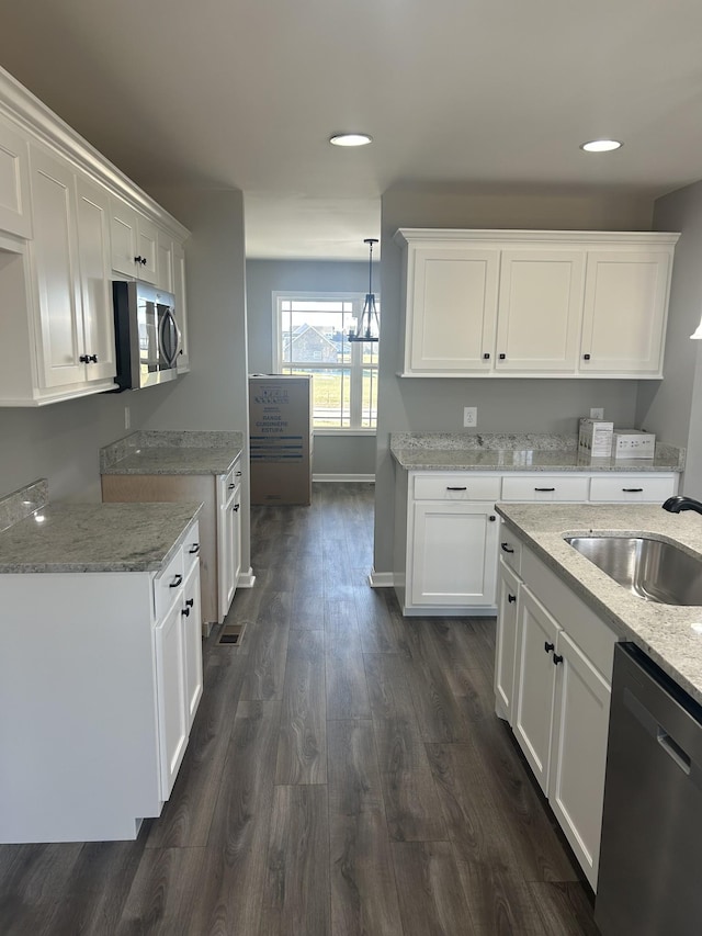 kitchen featuring light stone countertops, dishwasher, dark hardwood / wood-style floors, decorative light fixtures, and white cabinets