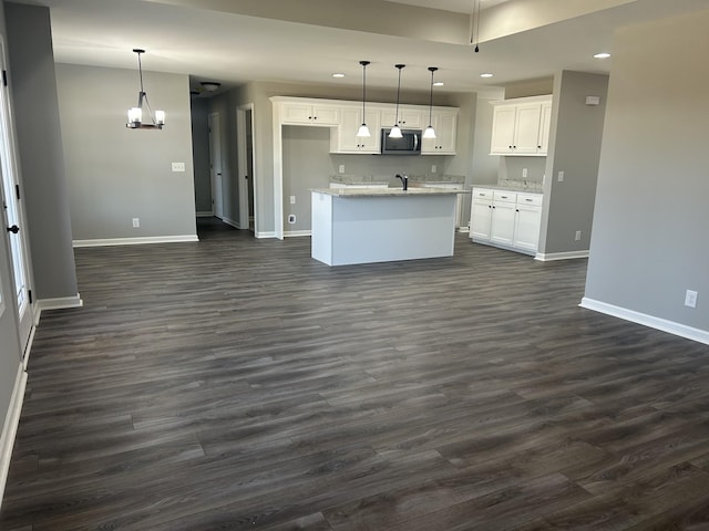 kitchen featuring white cabinets, hanging light fixtures, and a kitchen island with sink