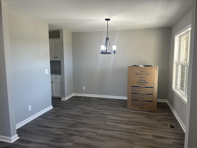 unfurnished dining area featuring dark hardwood / wood-style flooring and an inviting chandelier