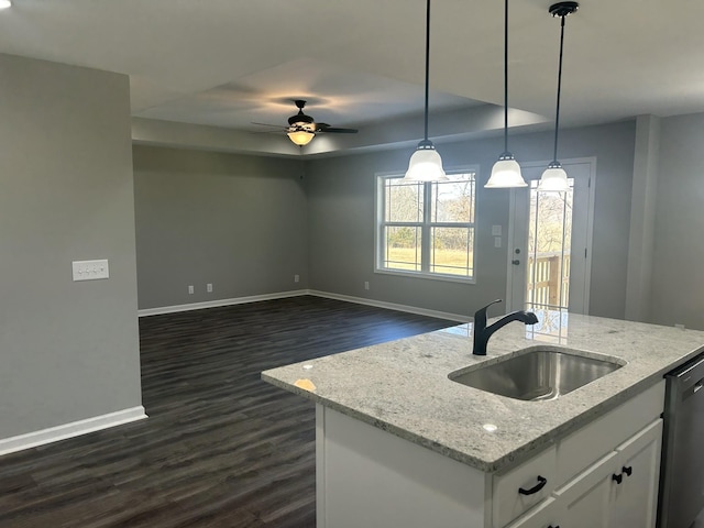 kitchen with white cabinets, a kitchen island with sink, light stone countertops, sink, and decorative light fixtures