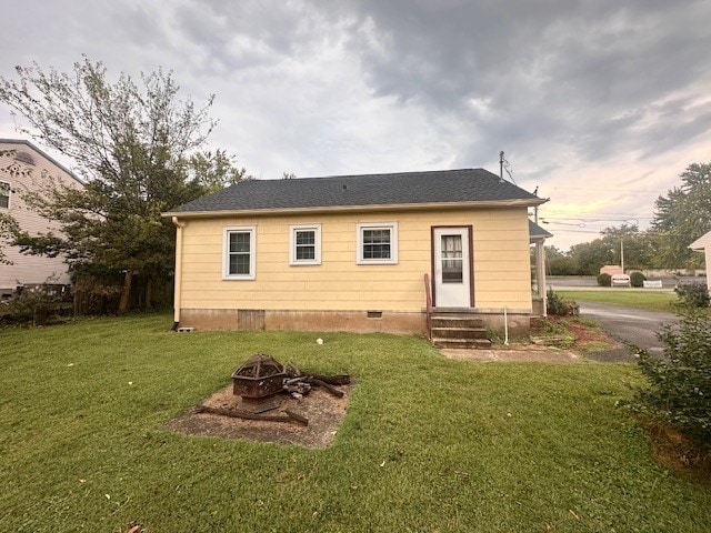 back of house with a yard and an outdoor fire pit