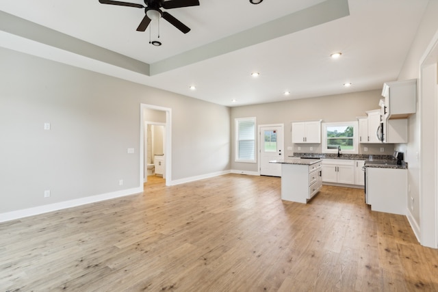 kitchen featuring ceiling fan, light hardwood / wood-style flooring, stainless steel gas range, white cabinetry, and a center island