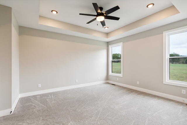 carpeted spare room featuring a raised ceiling and ceiling fan