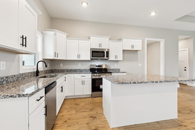 kitchen featuring white cabinets, a center island, appliances with stainless steel finishes, and sink