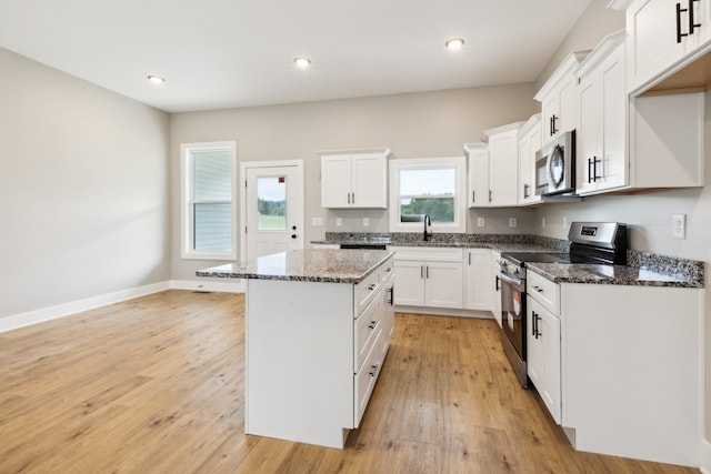 kitchen featuring light hardwood / wood-style floors, white cabinetry, a center island, and stainless steel appliances