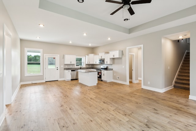 kitchen featuring ceiling fan, white cabinetry, appliances with stainless steel finishes, a center island, and light hardwood / wood-style floors