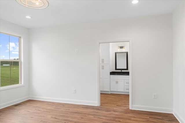 spare room with light hardwood / wood-style flooring, sink, and a wealth of natural light