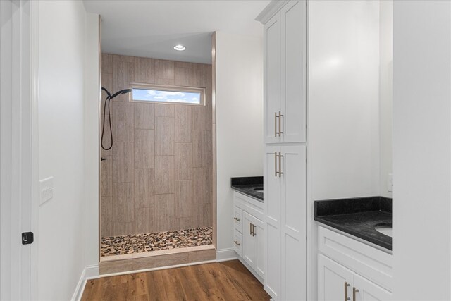 bathroom featuring hardwood / wood-style floors, vanity, and tiled shower