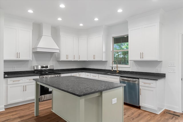 kitchen featuring sink, white cabinetry, a kitchen island, custom range hood, and appliances with stainless steel finishes