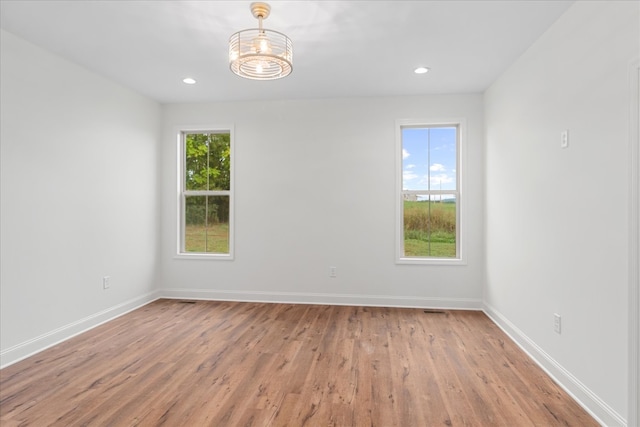 empty room featuring a notable chandelier, hardwood / wood-style flooring, and plenty of natural light