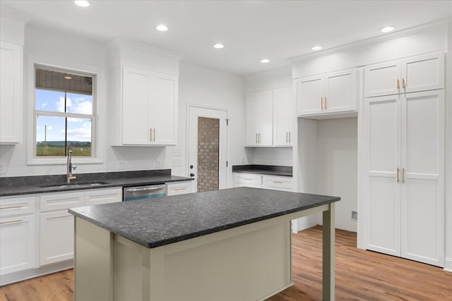 kitchen with white cabinets, sink, stainless steel dishwasher, a kitchen island, and light wood-type flooring