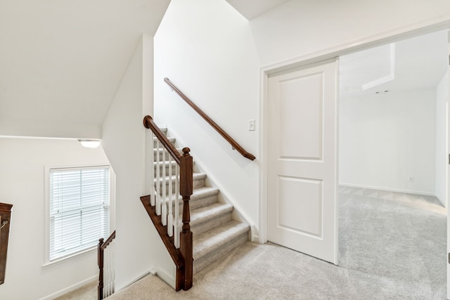 staircase featuring vaulted ceiling and carpet flooring