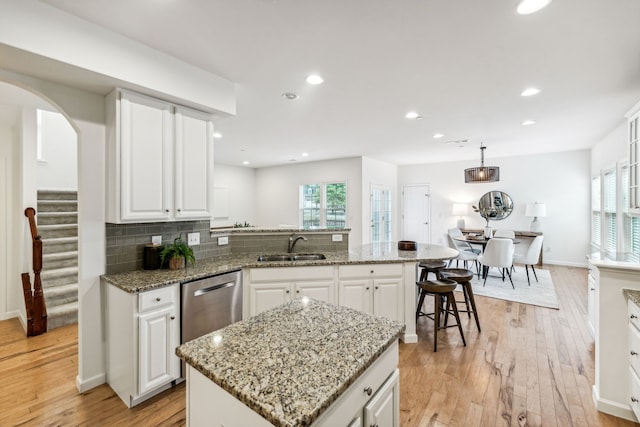 kitchen featuring light wood-type flooring, a kitchen island, pendant lighting, and white cabinetry