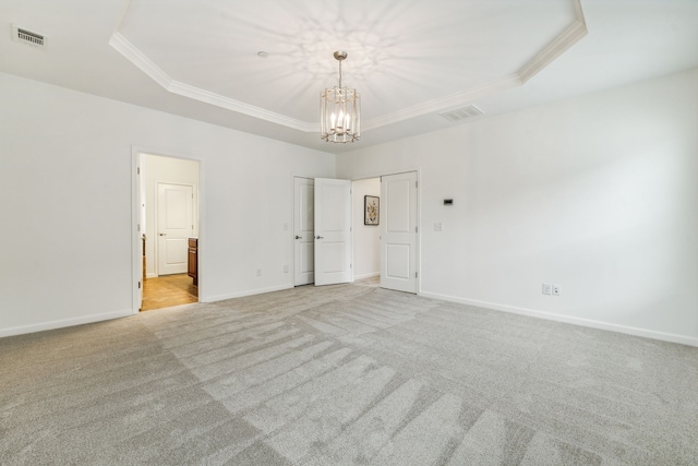 unfurnished room with an inviting chandelier, a raised ceiling, and light carpet