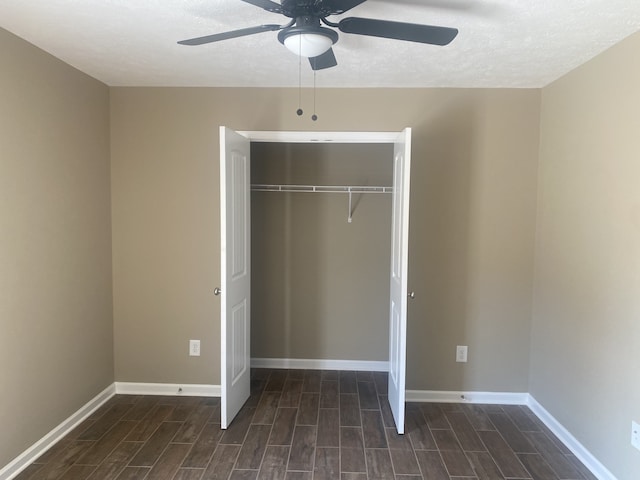 unfurnished bedroom with a textured ceiling, dark hardwood / wood-style floors, ceiling fan, and a closet