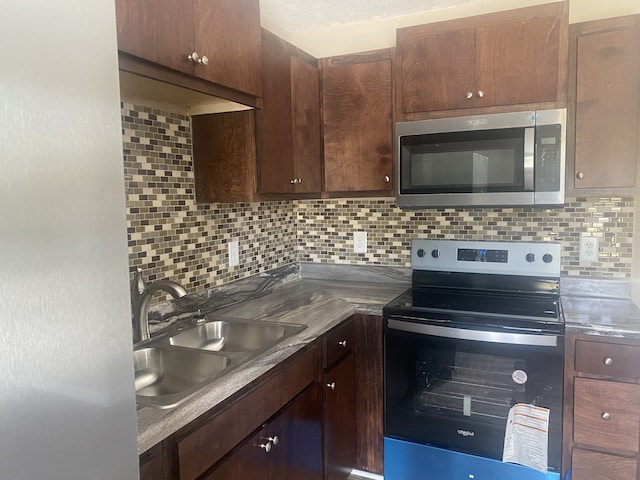 kitchen featuring stainless steel appliances, dark brown cabinetry, tasteful backsplash, and sink