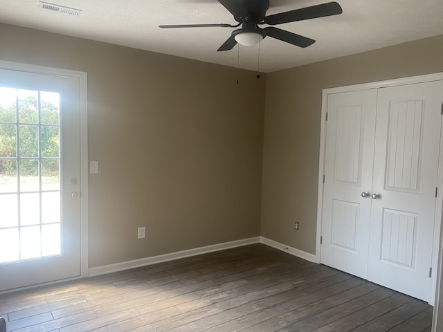 unfurnished bedroom with a closet, ceiling fan, dark wood-type flooring, and a textured ceiling