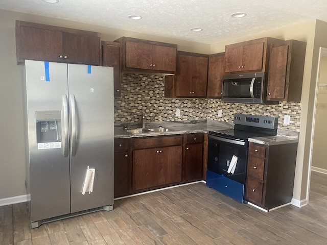 kitchen featuring dark brown cabinetry, stainless steel appliances, sink, and dark hardwood / wood-style flooring