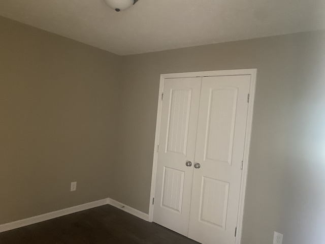 unfurnished bedroom featuring a closet and dark hardwood / wood-style floors