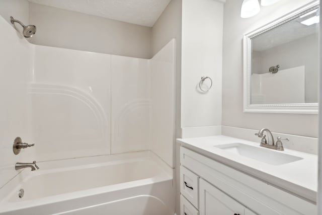 bathroom featuring a textured ceiling, vanity, and  shower combination