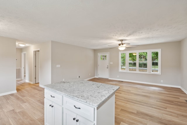 kitchen featuring light hardwood / wood-style floors, ceiling fan, light stone counters, and white cabinets