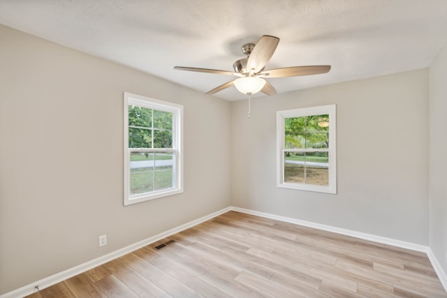 spare room featuring light wood-type flooring, a textured ceiling, and ceiling fan