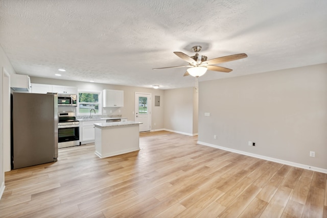 kitchen with ceiling fan, white cabinets, a textured ceiling, appliances with stainless steel finishes, and light hardwood / wood-style floors