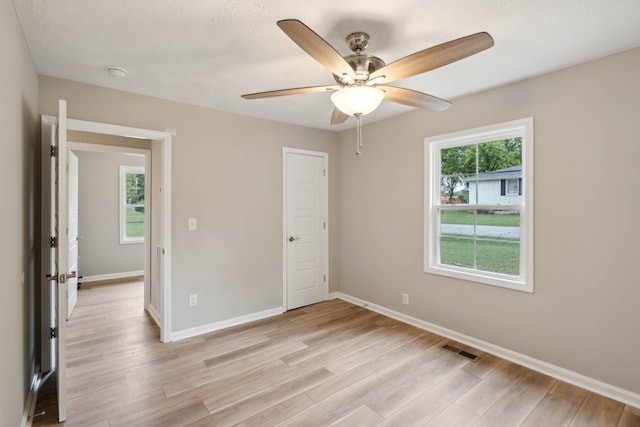 unfurnished bedroom featuring ceiling fan, light wood-type flooring, and multiple windows