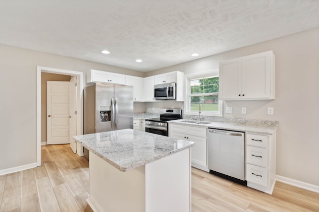 kitchen featuring a center island, sink, white cabinetry, light hardwood / wood-style flooring, and stainless steel appliances