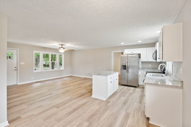 kitchen featuring appliances with stainless steel finishes, light hardwood / wood-style floors, a kitchen island, ceiling fan, and sink