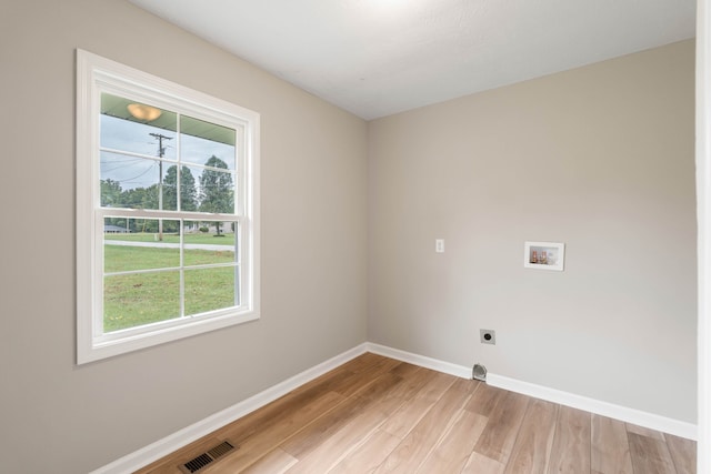 washroom featuring light wood-type flooring, hookup for a washing machine, electric dryer hookup, and a wealth of natural light