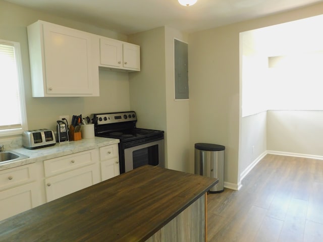 kitchen with light hardwood / wood-style floors, electric panel, stainless steel range with electric cooktop, white cabinets, and butcher block counters