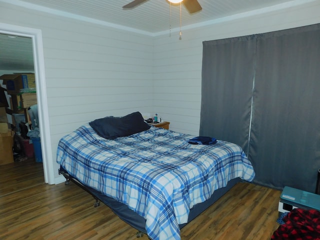 bedroom with wood walls, ceiling fan, and dark wood-type flooring