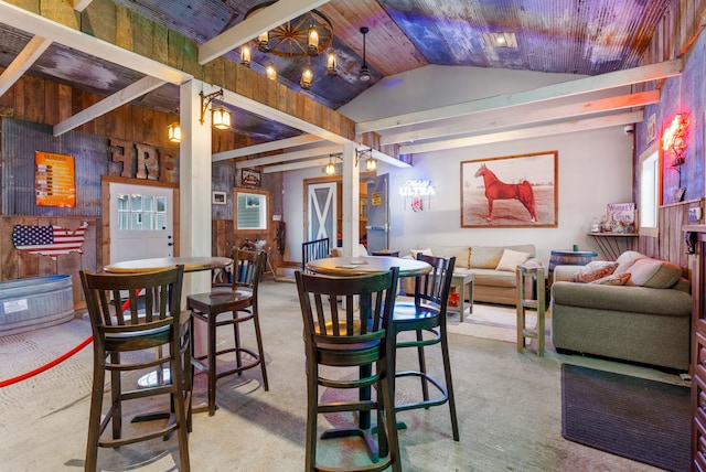 dining room featuring vaulted ceiling with beams and wooden walls