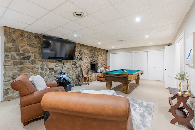 recreation room with pool table, a stone fireplace, light colored carpet, and a drop ceiling