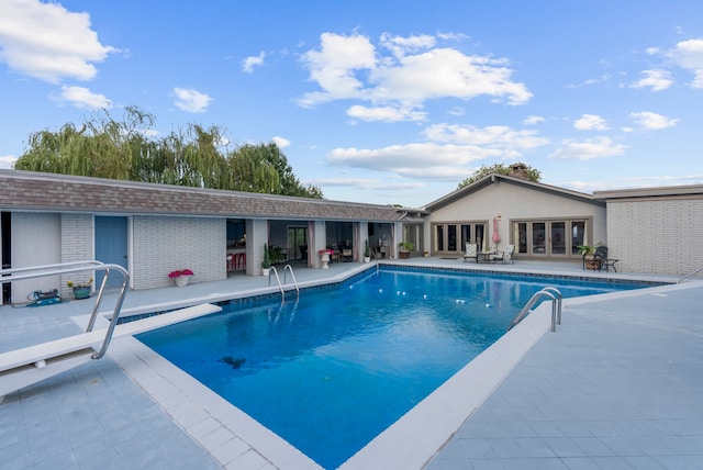 view of swimming pool featuring a diving board and a patio area