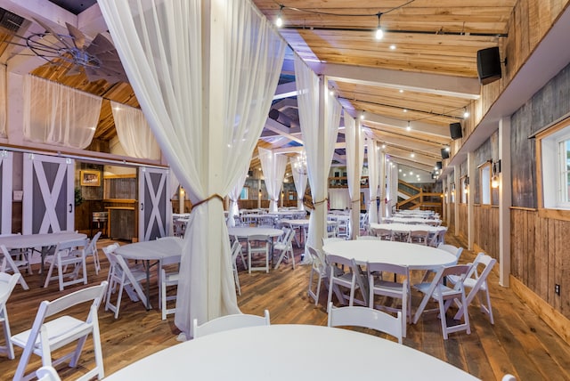 dining area featuring wood-type flooring, wooden walls, lofted ceiling, and wooden ceiling