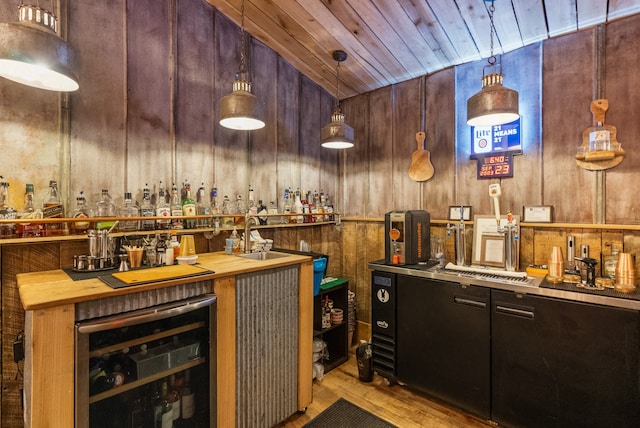 bar with wine cooler, decorative light fixtures, wooden ceiling, light hardwood / wood-style floors, and wood counters