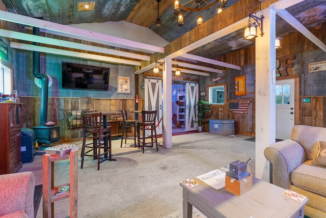 living room featuring lofted ceiling with beams, a wood stove, and wooden walls