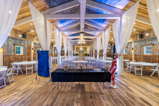 interior space featuring wooden walls, lofted ceiling with beams, an inviting chandelier, and hardwood / wood-style floors