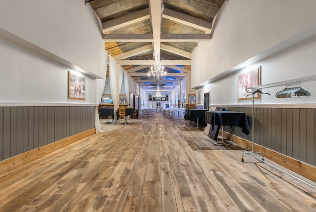 misc room featuring beam ceiling, wooden walls, hardwood / wood-style floors, and a notable chandelier