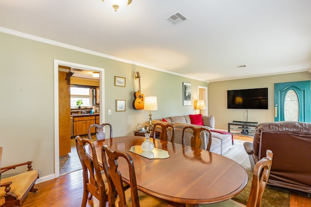 dining space with crown molding and hardwood / wood-style flooring