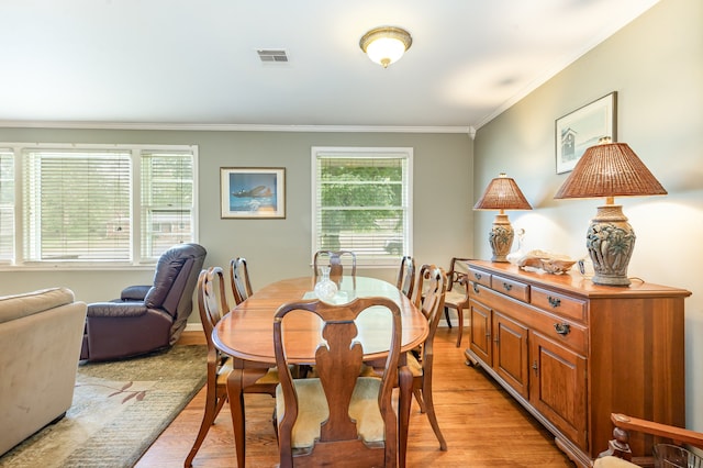 dining room with light hardwood / wood-style flooring and crown molding