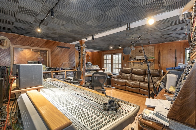 miscellaneous room with brick wall, track lighting, wooden walls, and hardwood / wood-style floors