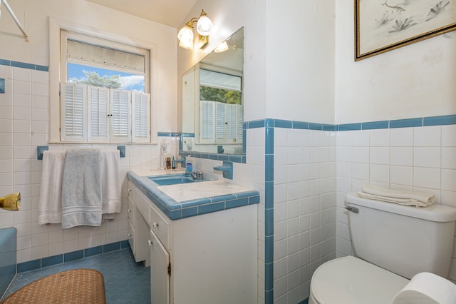 bathroom featuring vanity, toilet, and tile walls