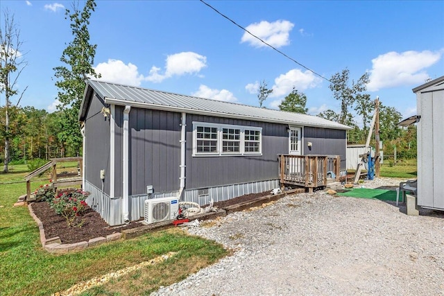 view of front of property featuring ac unit, a wooden deck, a front lawn, and an outbuilding