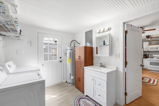 clothes washing area with wood walls, sink, light hardwood / wood-style flooring, separate washer and dryer, and electric water heater