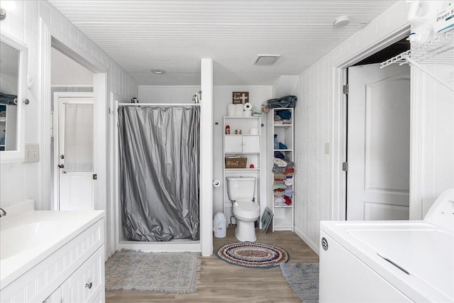 bathroom with vanity, toilet, washer / dryer, hardwood / wood-style floors, and a shower with shower curtain